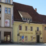 Und zu guter Letzt noch einmal das <a href="https://gedenkplaetze.info/widerstand/volkshaus-pirna"target="_blank" rel="noopener">Gasthaus Weißes Roß</a> und unter „Sport Wolf“ die dunkelbraune Holztür, durch die wir zu unserer Unterkunft im Hinterhof gelangten