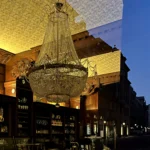 Durch die Eingangstür ins Kaffeehaus Riquet kurz vor Einbruch der Dunkelheit fotografiert geht das Interieur nahtlos in das sich spiegelnde Straßenbild über