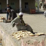Männer beim Auslegen des Brotes, das sie soeben beim Bäcker gekauft haben und nun auf die heiße Steinmauer legen, damit es aufgeht